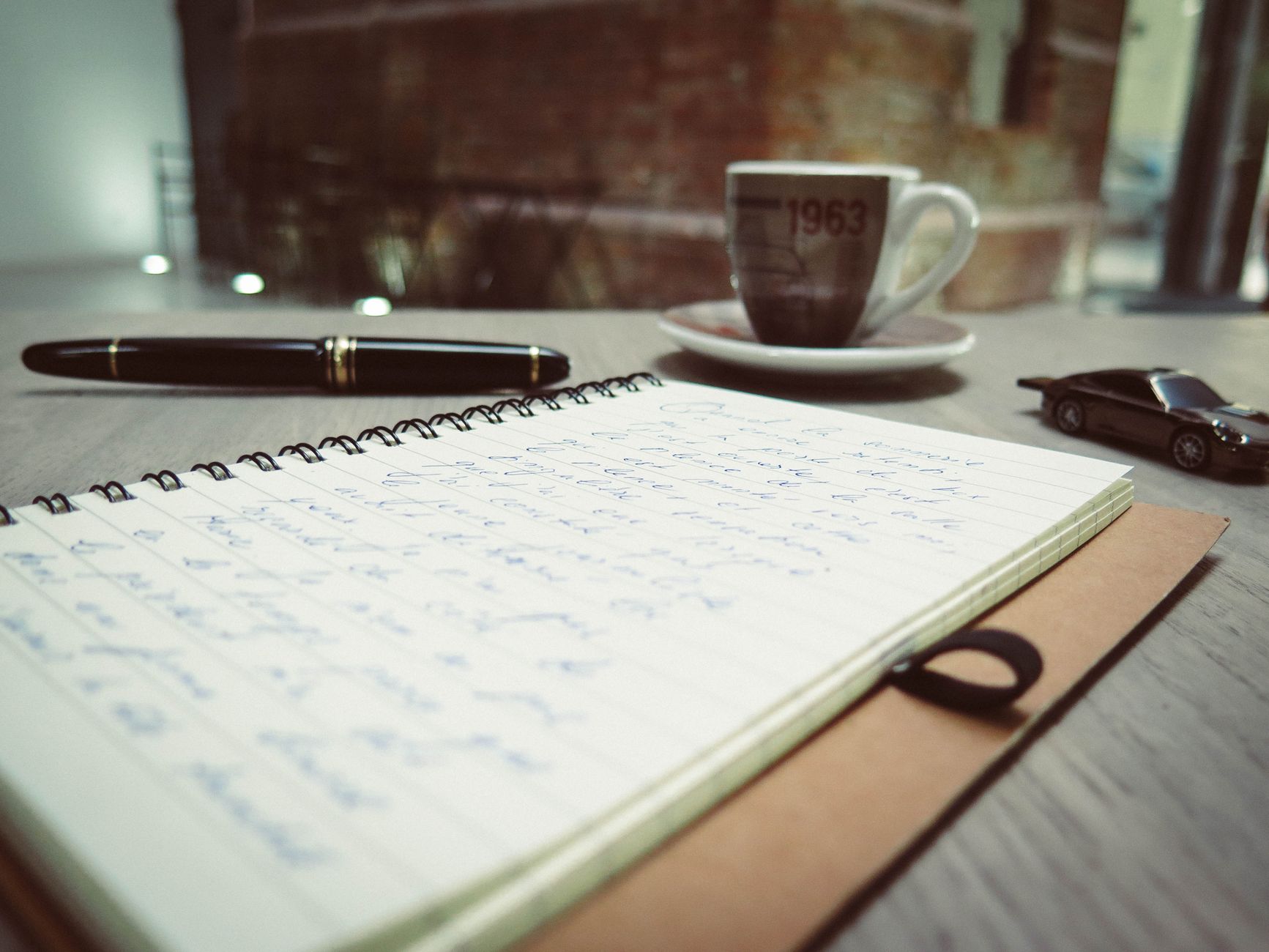 Scrivania calda e accogliente con una tazza di caffè, appunti scritti a mano e una penna, pronta per organizzare un corso o un e-book.